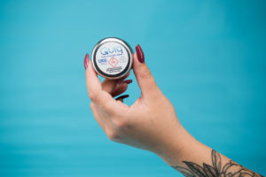 The hand of a woman is seen holding a Quiq THC-infused Extra Strenth Salve