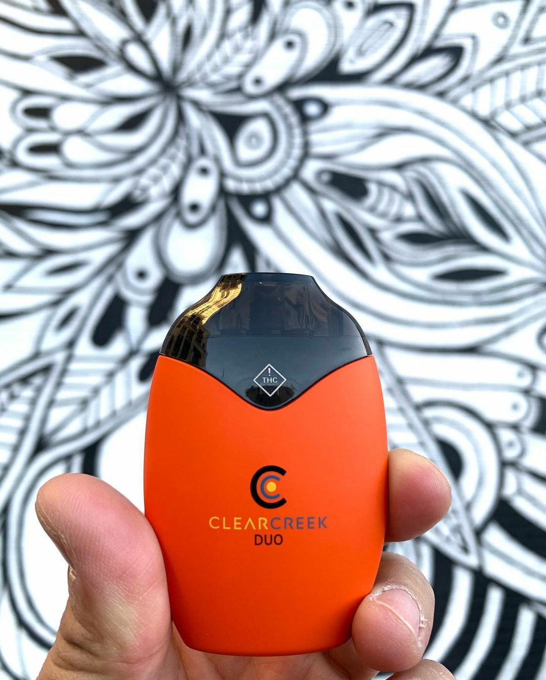 A man holding up a Clear Creek Extracts DUO pod up against a graphic black and white background. Before consuming, it's important to review Everything Consumers Should Know About Cannabis Vapes.